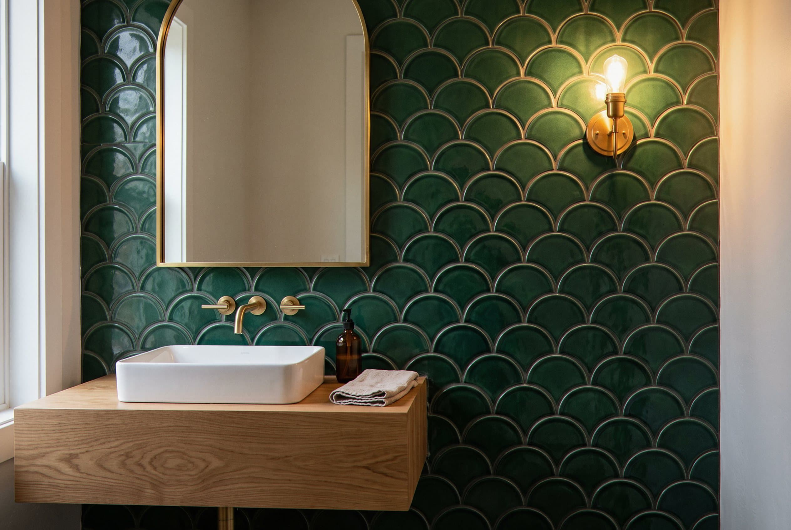 Green scalloped tile wall with arched mirror over sink