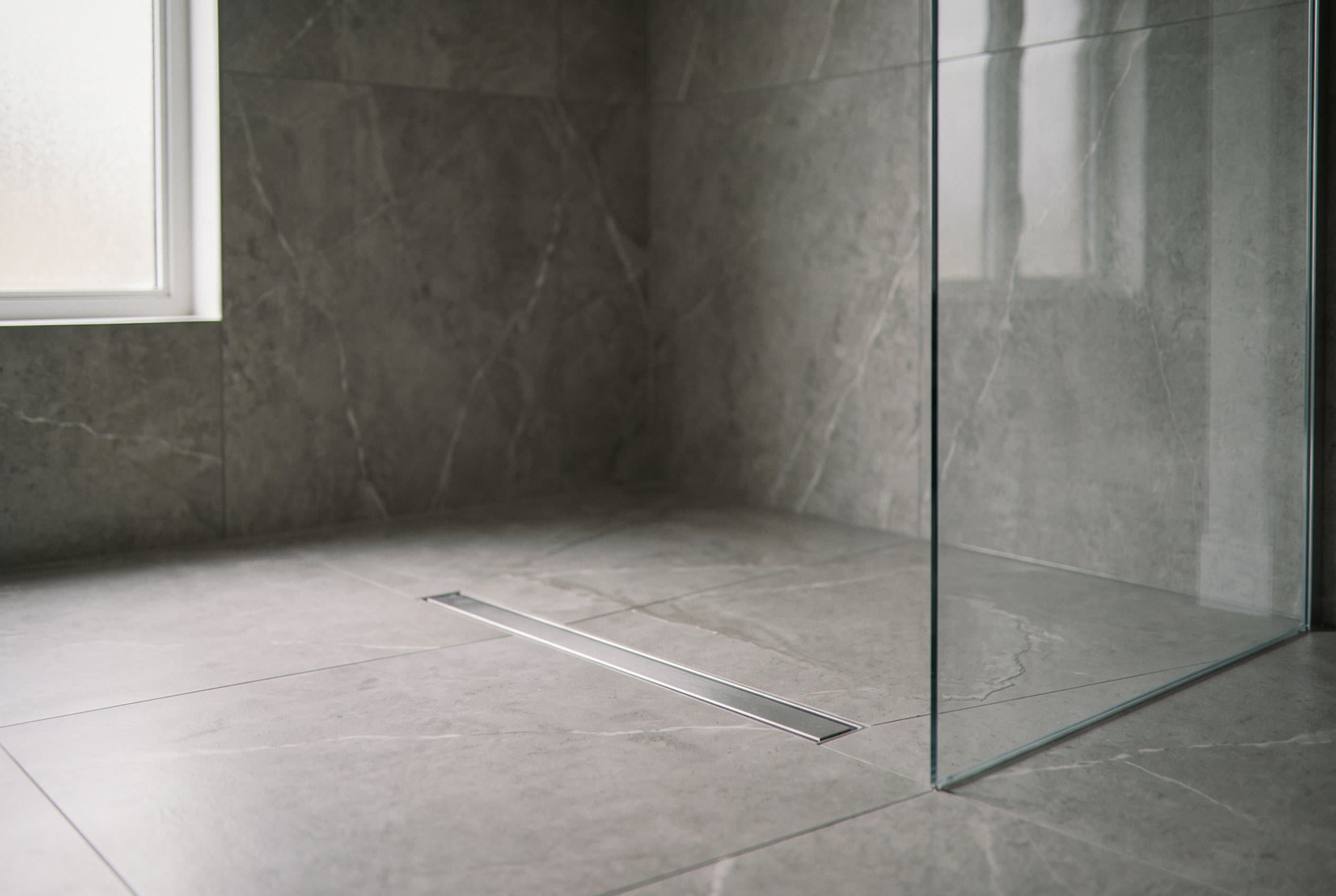 Frameless glass shower stall with gray large-format tile