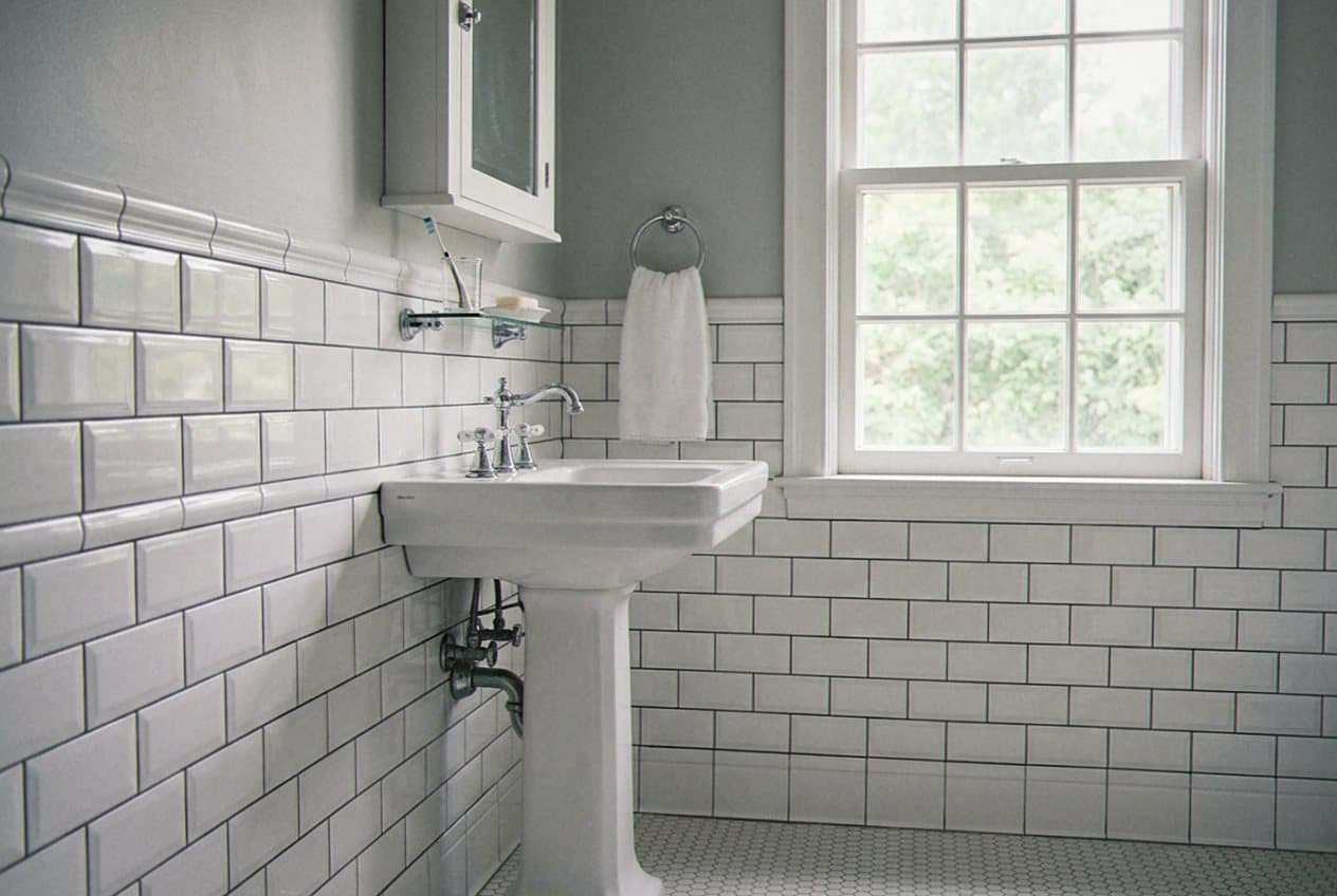 White subway tile wainscot around a pedestal sink