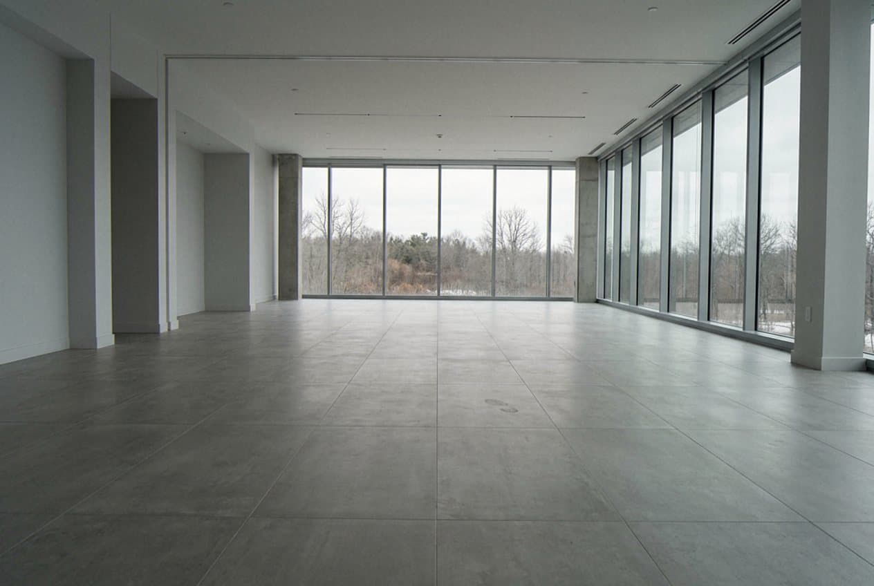 Large-format concrete-look tile floor in open glass room