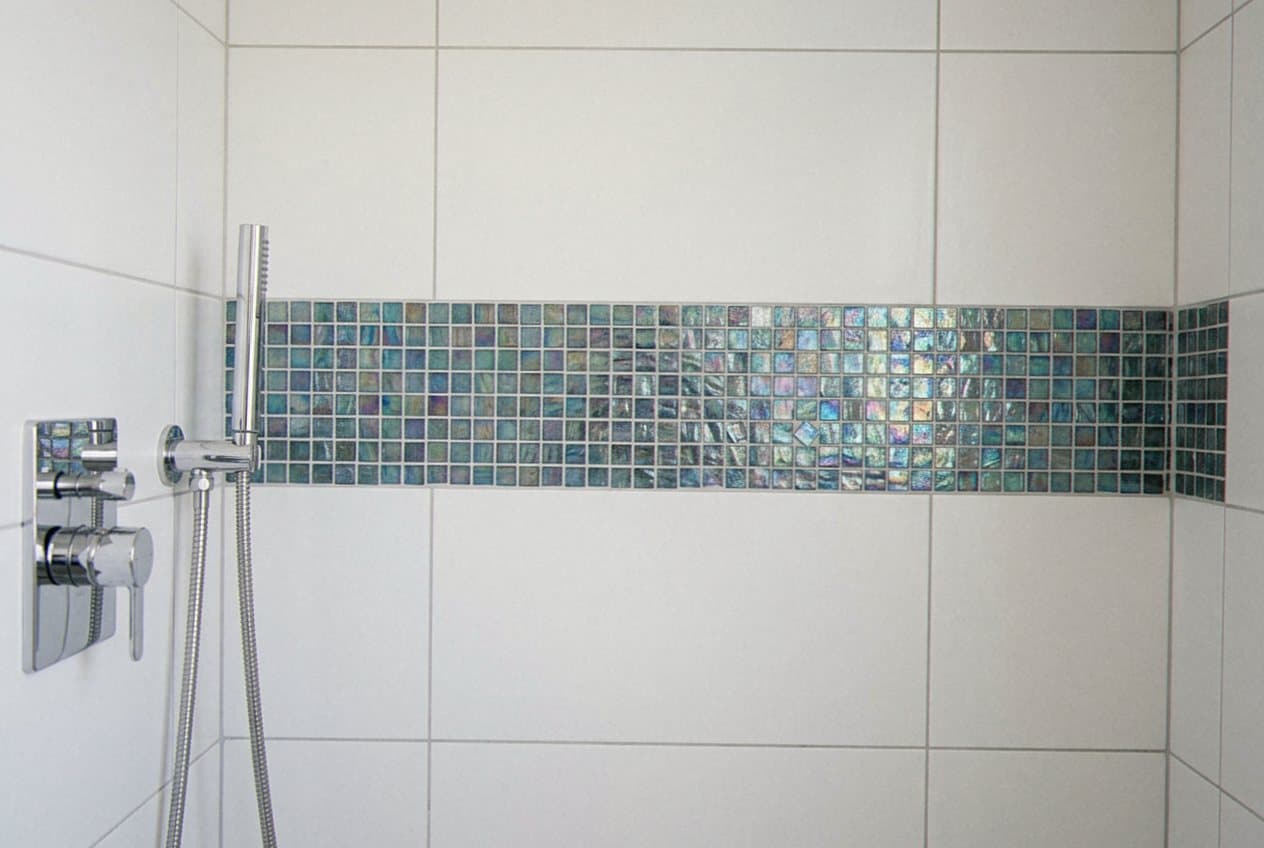 Teal glass mosaic accent stripe in white tiled shower