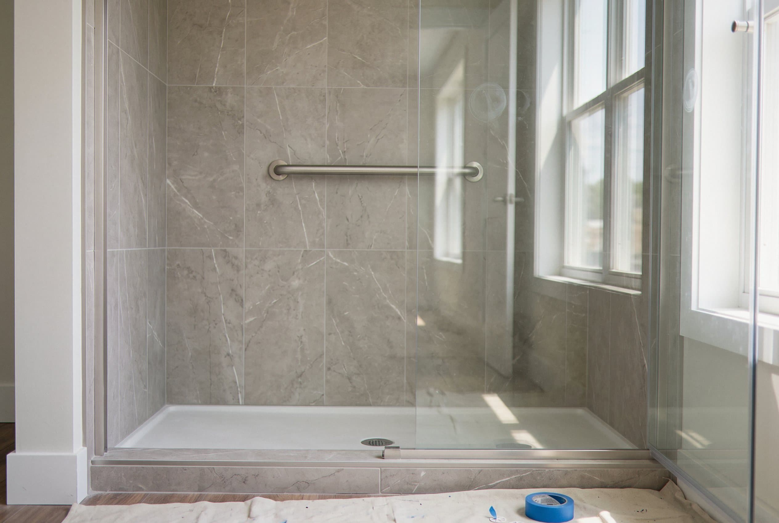Walk-in shower conversion with grab bar and marble tile